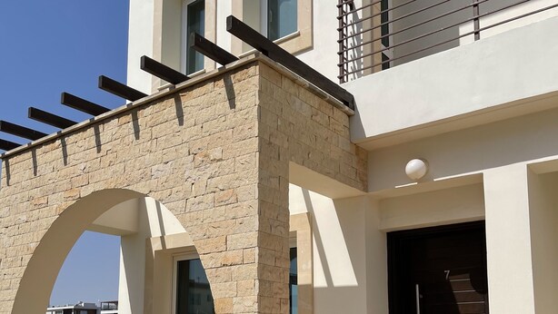 A modern two-story house with a stone archway leading to a covered patio area. - Beautiful Villa With Pool in Ayia Triada, Cyprus (Paralimni)