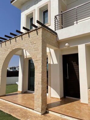 Et moderne hus med to etager og en stenbuet indgang til en overdækket patio.