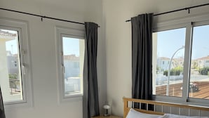 A bedroom with a bed, two windows, a nightstand, and a lamp. - Beautiful Villa With Pool in Ayia Triada, Cyprus (Paralimni)