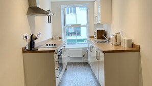 Et snævert køkken med et vindue, en indbygget komfur og en mikrobølgeovn.
