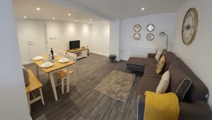 En moderne stue med sofa, spisebord og fjernsyn.