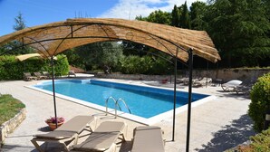 Une piscine dotée de chaises longues et d’une structure en forme de pergola.