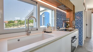 A modern kitchen with a large window, a built-in sink, and a kettle. - Cozy home in Partinico (Partinico)