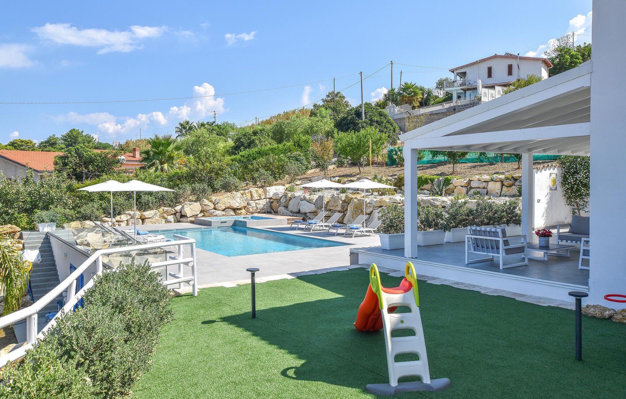 A swimming pool with a slide, a children's play area, and a covered seating area.
