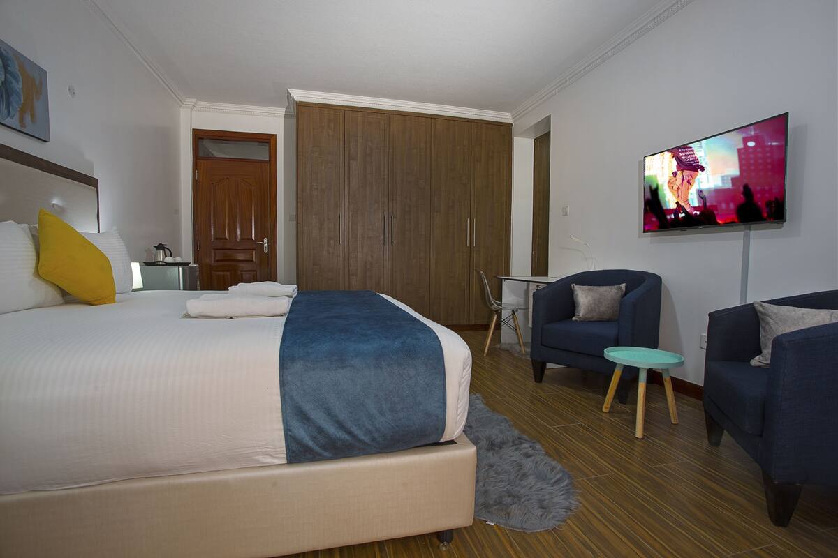 A hotel room with a bed, a TV, a desk, and two chairs.