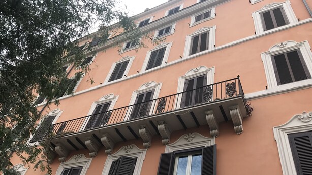 Un immeuble à plusieurs étages, doté de balcons, de cadres de fenêtres blancs et de volets noirs.