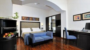 Une chambre d’hôtel avec un lit, un canapé bleu, un bureau et un téléviseur.