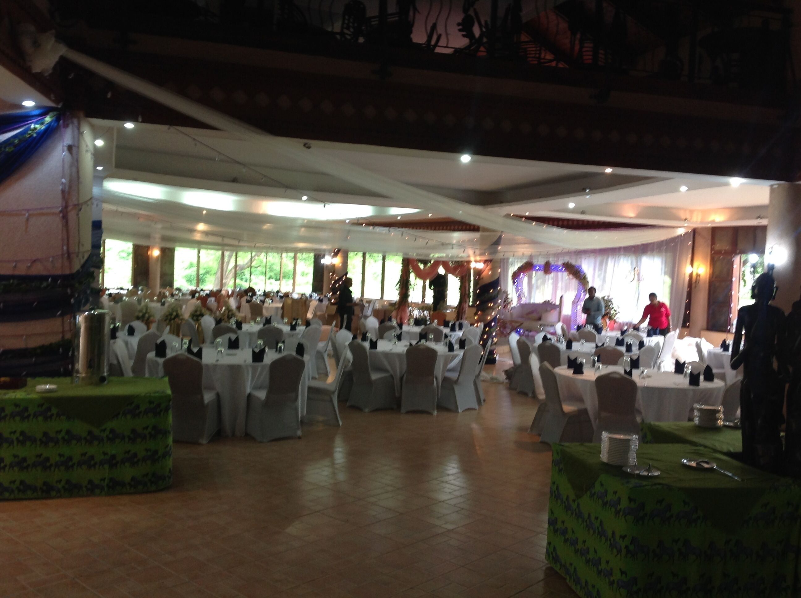 A banquet hall with round tables, chairs, and a stage.
