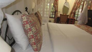 Una cama bien hecha con almohadas estampadas y una colcha blanca.