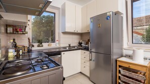 A modern kitchen with a gas stove, stainless steel refrigerator, and white cabinetry. - 3 bedroom beautiful apartment in Veli Losinj (Veli Losinj)