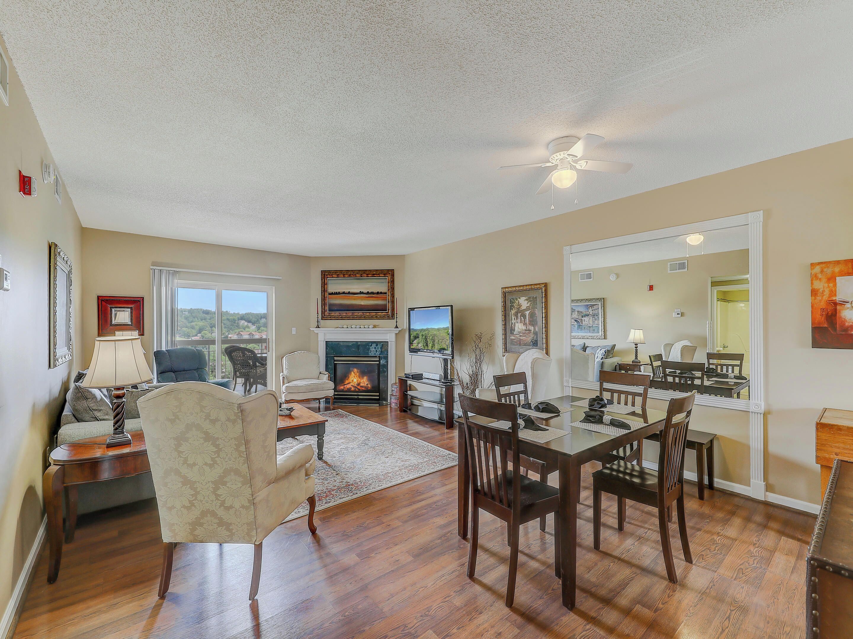 A spacious living room with a fireplace, dining area, and a large mirror reflecting the space.
