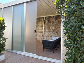 A sliding glass door leading to an outdoor patio with a stone wall, a wicker sofa, and a potted plant. - New Fabulous Villa Fichi Private Pool, private terrace WIFi (Martina Franca)