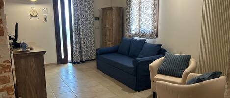 A living room with a sofa, armchair, and a small table with a lamp.