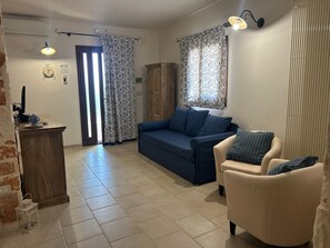 Un salon comprenant un canapé, un fauteuil et une petite table avec une lampe.