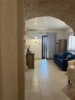A living room with a stone archway, a sofa, a cabinet, and a tiled floor. - New Fabulous Villa Fichi Private Pool, private terrace WIFi (Martina Franca)