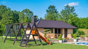Une maison avec une balançoire, un toboggan et une piscine.