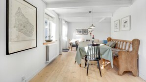 Un coin repas avec une table dressée pour deux personnes, un banc en bois et une carte accrochée au mur.
