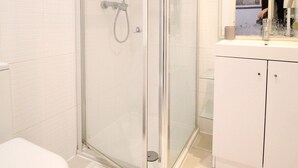 Une salle de bain avec une douche à parois de verre, des toilettes blanches et un lavabo avec un miroir au-dessus.