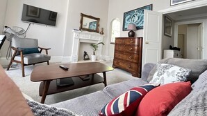 Un salon avec une cheminée, un canapé, une table basse, un téléviseur et un ventilateur.
