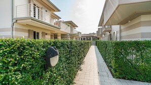 Un edificio residencial con un sendero pavimentado, un seto y un buzón.