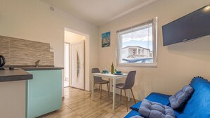 A compact living space with a kitchenette, dining area, and a sofa with cushions. - Stunning apartment in Vir with WiFi (Vir)
