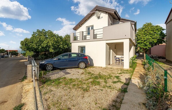 Une maison moderne à deux étages, avec une voiture garée dans l’allée.