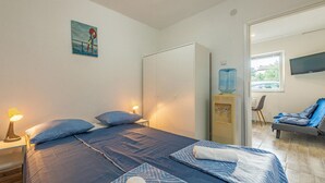 A bedroom with a bed, bedside lamps, a water dispenser, a TV, and a chair. - Stunning apartment in Vir with WiFi (Vir)