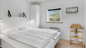 Et soveværelse med seng, et vindue med udsigt, en reol med genstande og en stol.