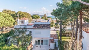 Un quartier résidentiel avec des maisons blanches, des toits recouverts de tuiles rouges et une vue dégagée sur la mer en arrière-plan.