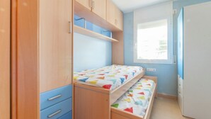 Une chambre avec un lit superposé, une armoire en bois et une fenêtre avec des stores.