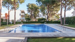 Une piscine rectangulaire avec deux échelles de chaque côté, entourée d’une terrasse dallée et d’une pelouse.