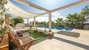 An outdoor pool area with a wooden deck, lounge chairs, and a covered seating area. - Awesome apartment in Vir with WiFi (Vir)
