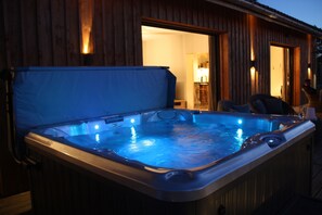 Un bain à remous doté d’une couverture bleue, de parois extérieures en bois et d’une porte visible donnant accès à un espace intérieur.