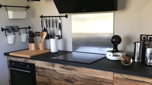 Eine moderne Küche mit einem schwarzen Herd, Holzschränken, hängenden Küchenutensilien und einer Kaffeemaschine.