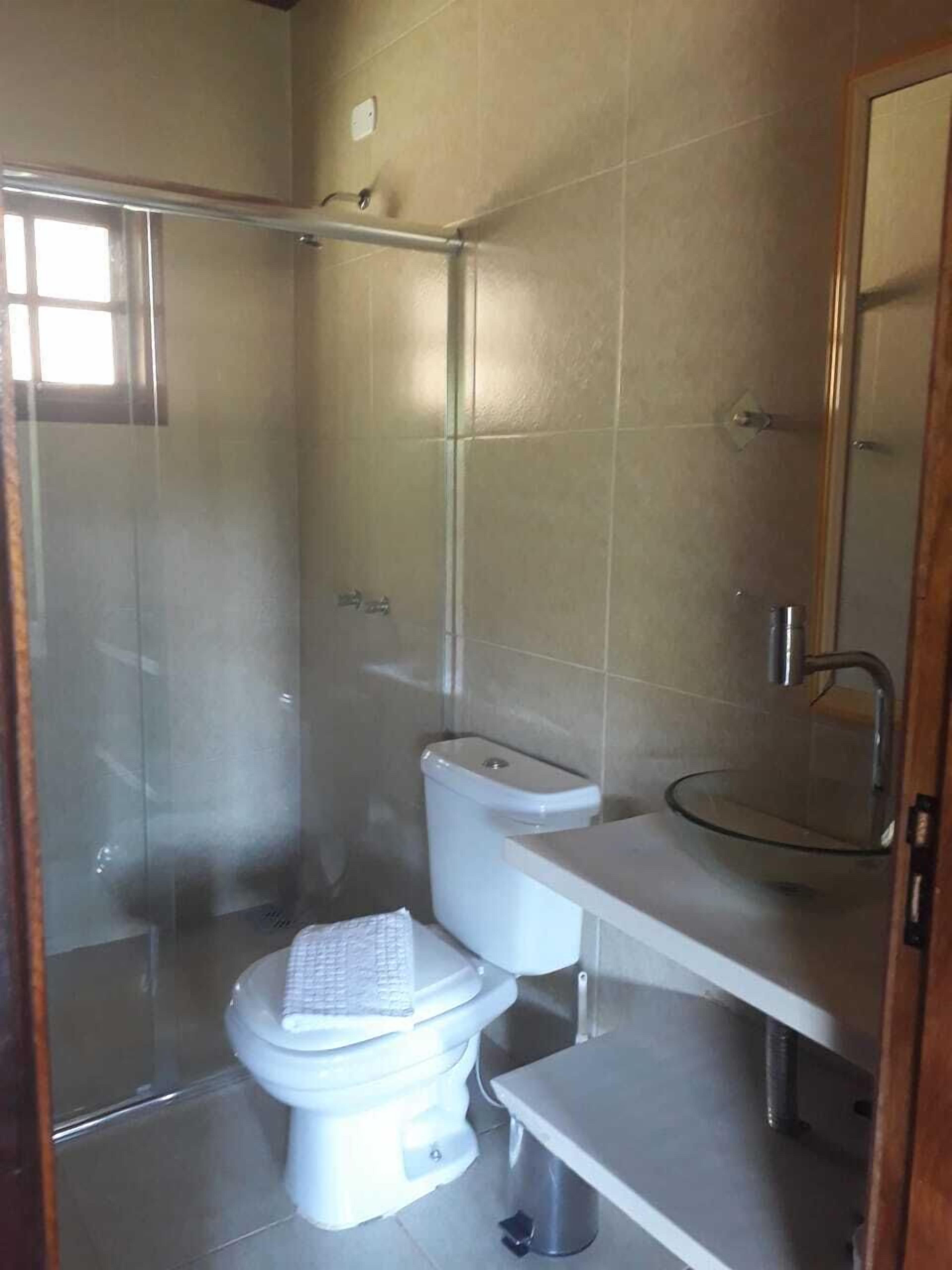 A bathroom with a toilet, a glass shower enclosure, and a sink with a mirror.