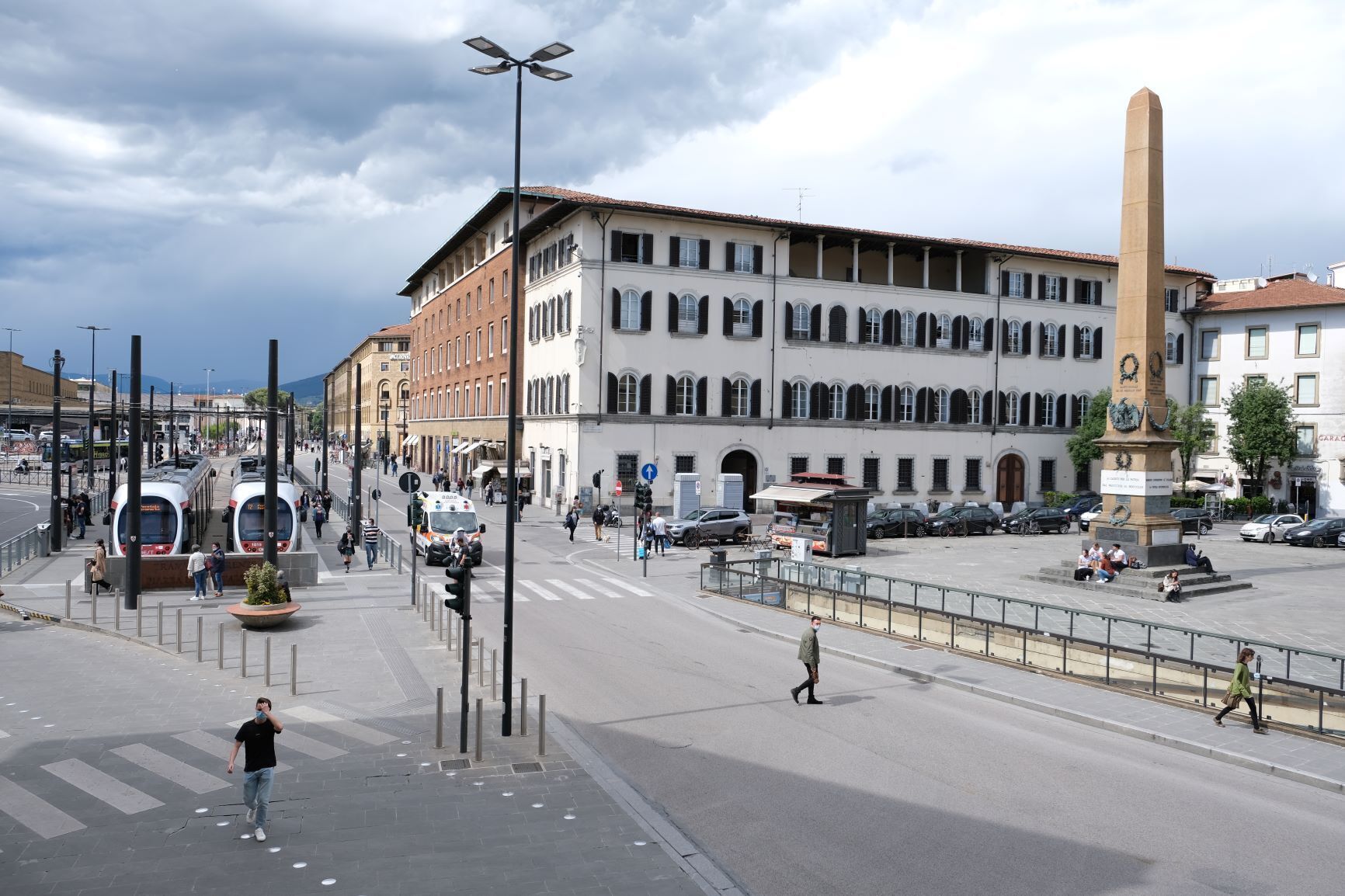 A city square with a tram, buildings, and a monument.