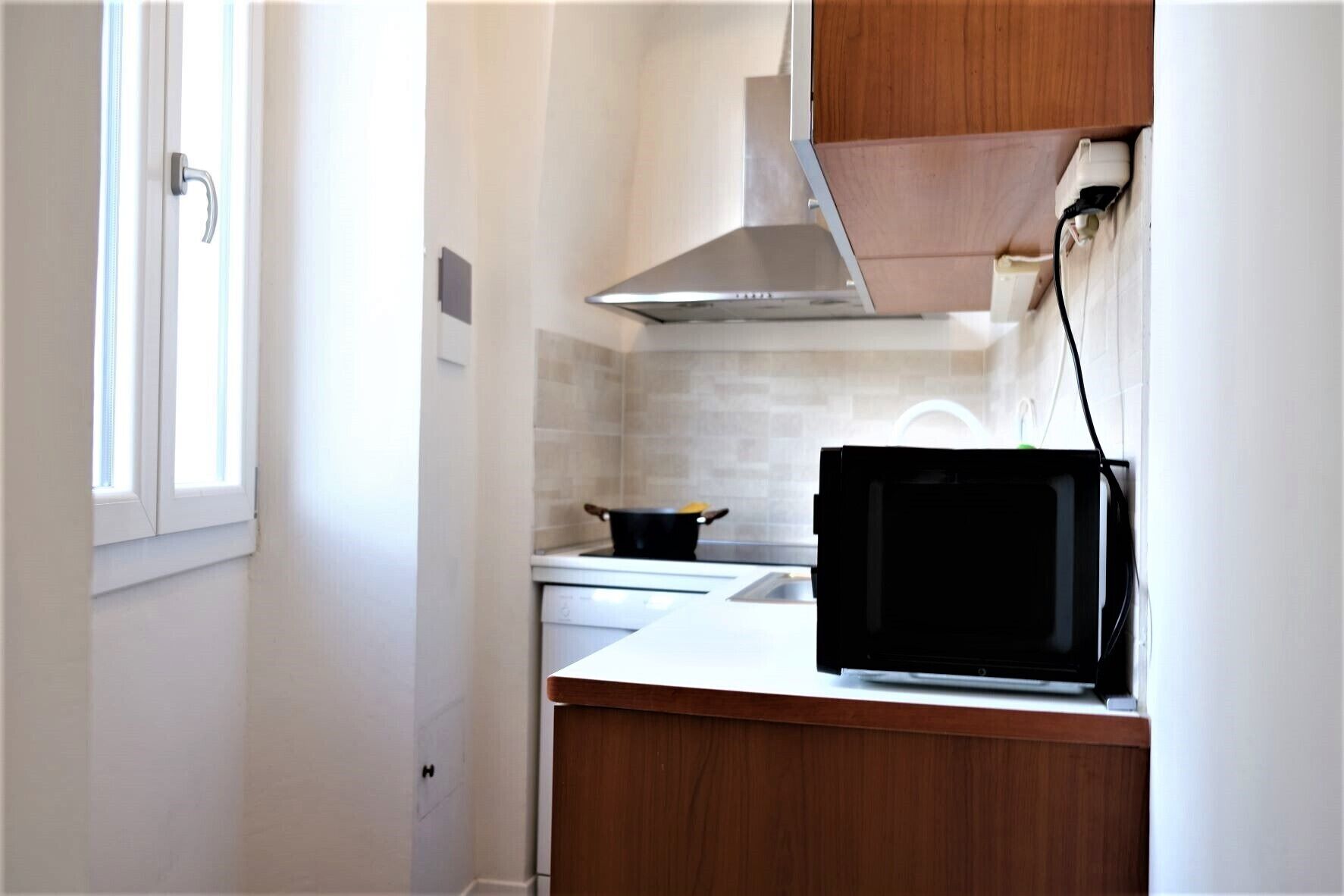 Cocina compacta con estufa, microondas y armarios de madera.
