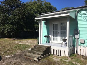 Ein kleines Haus mit Veranda, Grill und Stromkasten.