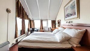 A hotel room with a large bed, a desk, a chair, and a window with curtains. - Chesterfield Hotel (Trondheim)