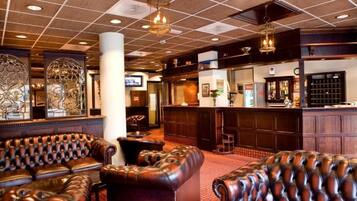 A lobby with leather sofas, a bar area, and decorative wall art.