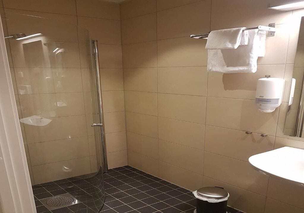 A small bathroom with a shower, toilet, sink, and a towel rack.