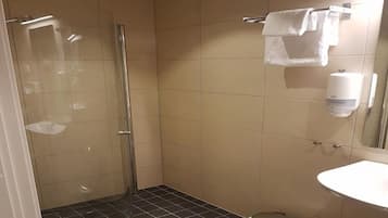 A small bathroom with a shower, toilet, sink, and a towel rack.