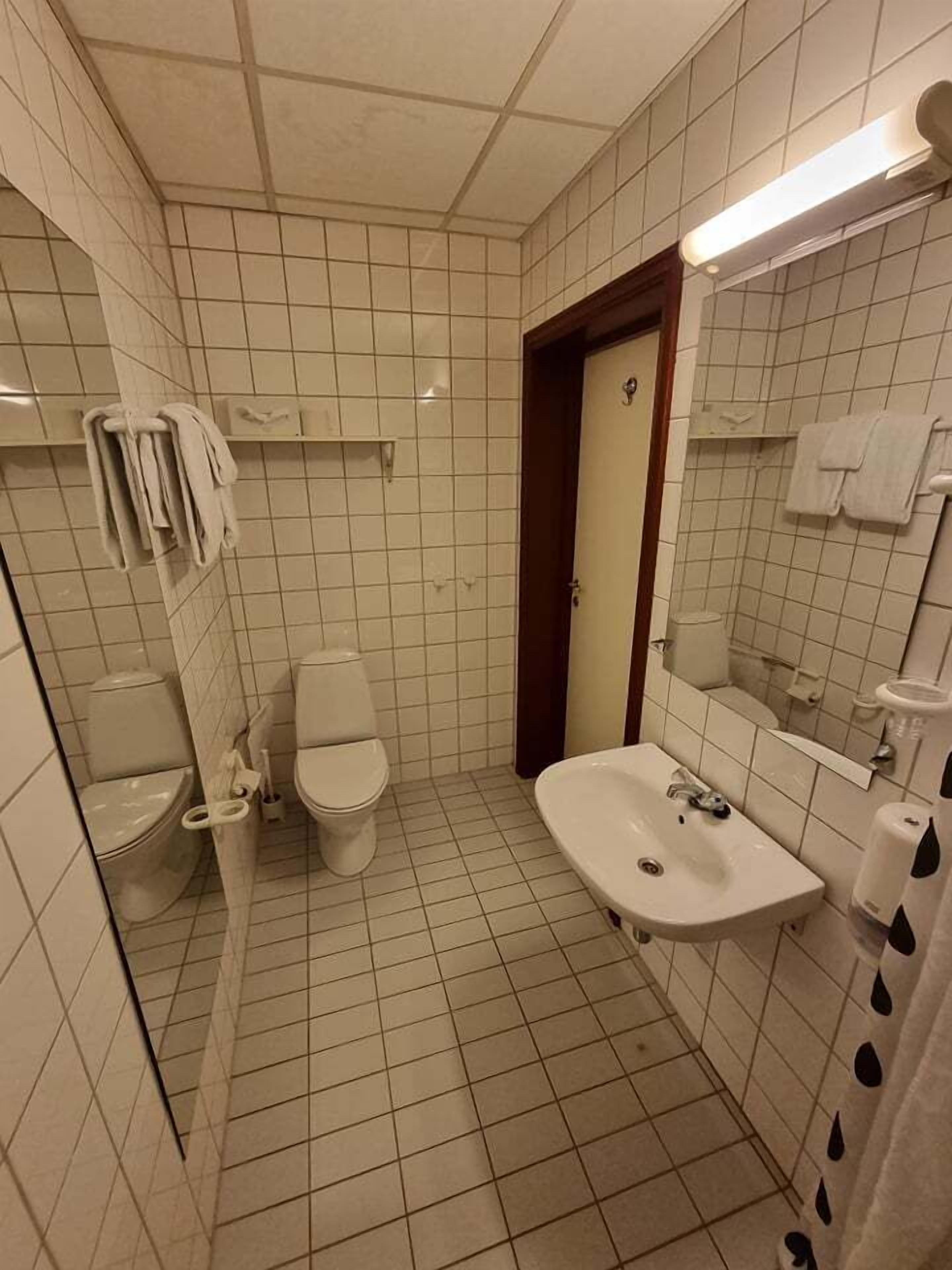 Een kleine badkamer met tegels, een toilet, een wastafel en een spiegel.