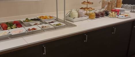 A buffet setup with various food items and condiments.