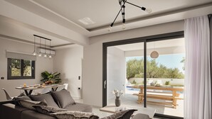 Un soggiorno moderno con un divano, un'area pranzo con tavolo e sedie, e vista su una zona piscina all'aperto.
