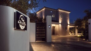 Un edificio moderno con ingresso carrabile, segnaletica illuminata e viale ben illuminato al crepuscolo.