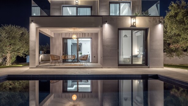 Una moderna casa a due piani con piscina di fronte.