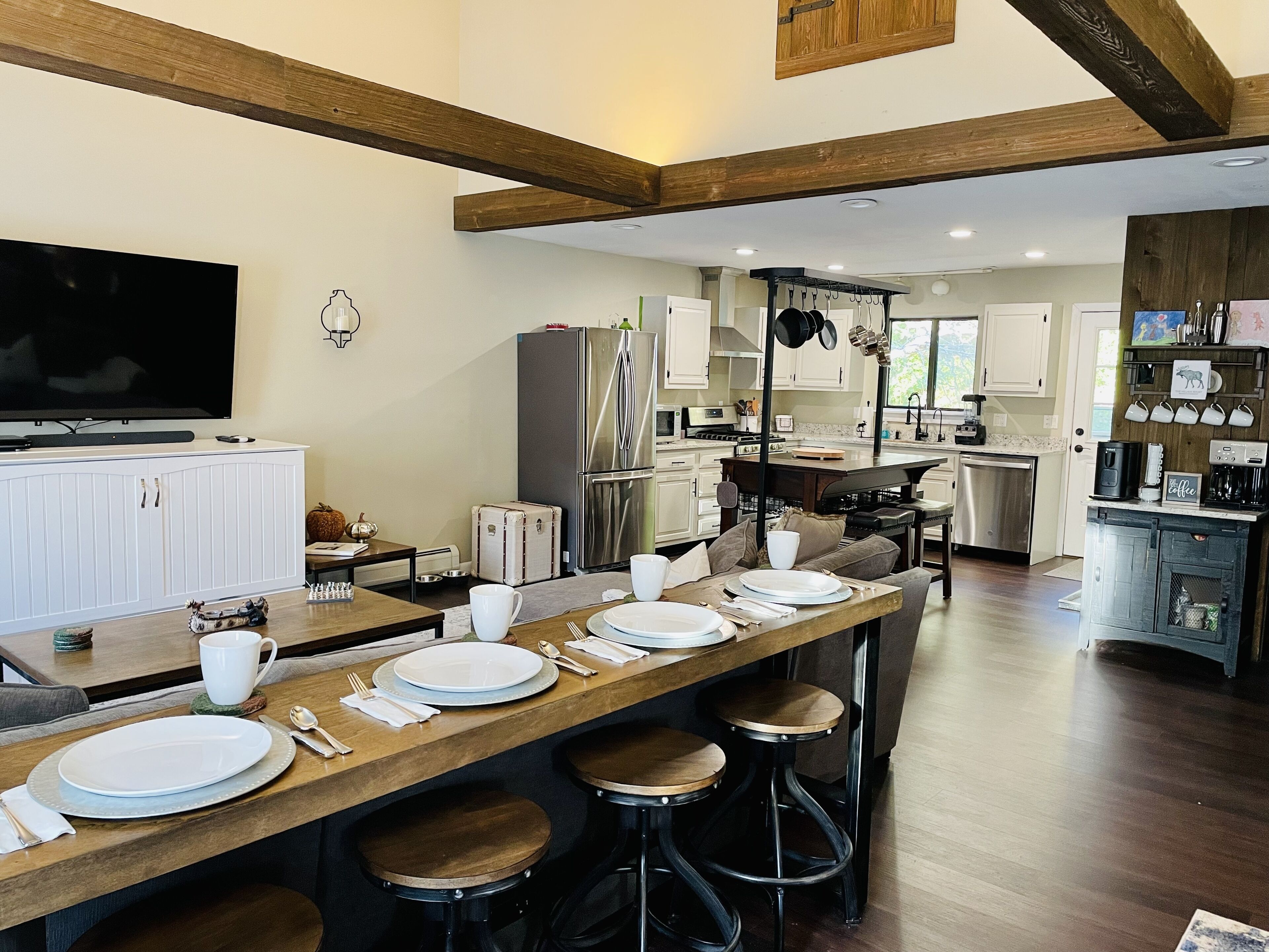 A modern kitchen with a central island, stainless steel appliances, and a dining area with stools.