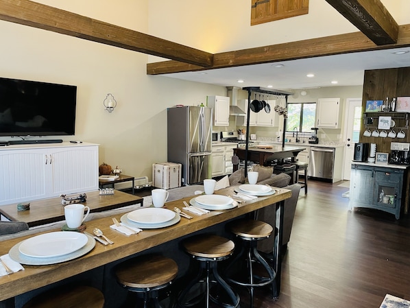 A modern kitchen with a central island, stainless steel appliances, and a dining area with stools.
