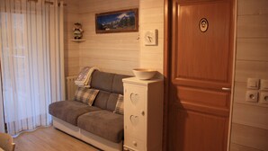 A cozy room with a wooden door, a white cabinet with heart-shaped cutouts, a brown sofa, and a framed picture on the wall. - 200 m from the Saint Gervais les Bains cable car  (Saint-Gervais-les-Bains)